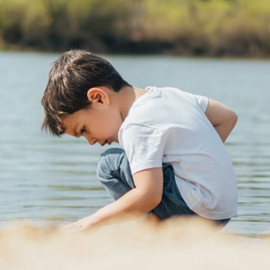 panoramic shot of cute boy sitting near pond